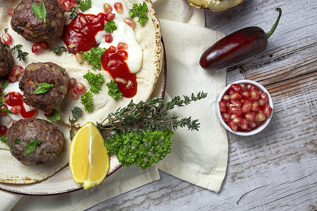 Traditionelle hausgemachte Rind- und Lammfleischbällchen mit arabischem Brot, Tomatensauce, Granatapfel und Kräutern. Halal-Essen