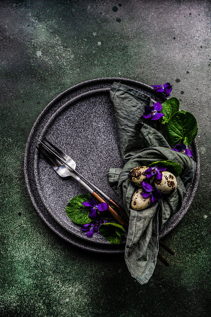Spring table setting with wild blue viola flower on black plate set