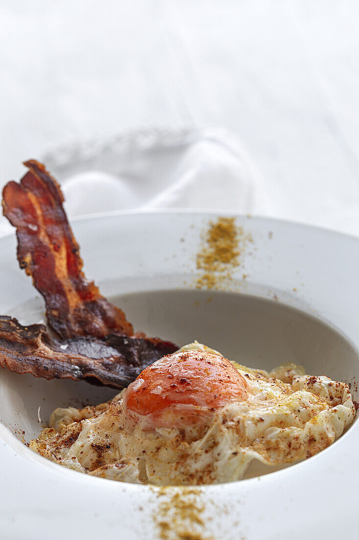 Overhead view of tasty eggs with fried bacon strips on plate