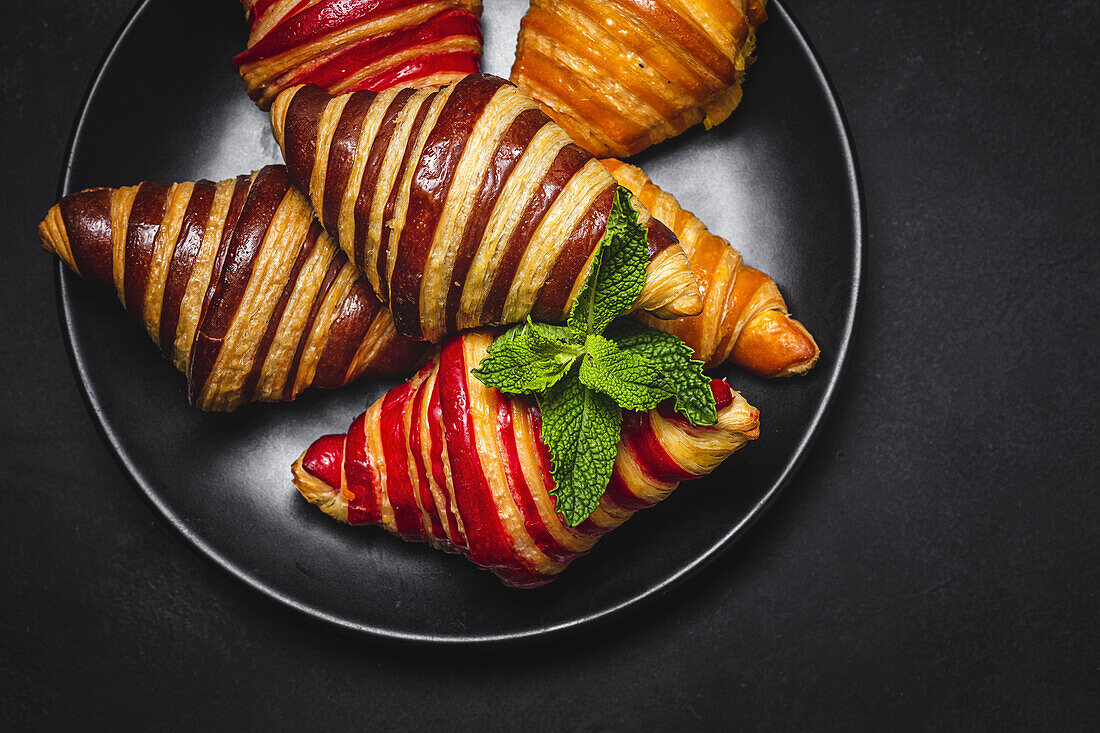 Blick von oben auf verschiedene süße Croissants, die in einem Korb auf dem Frühstückstisch serviert werden