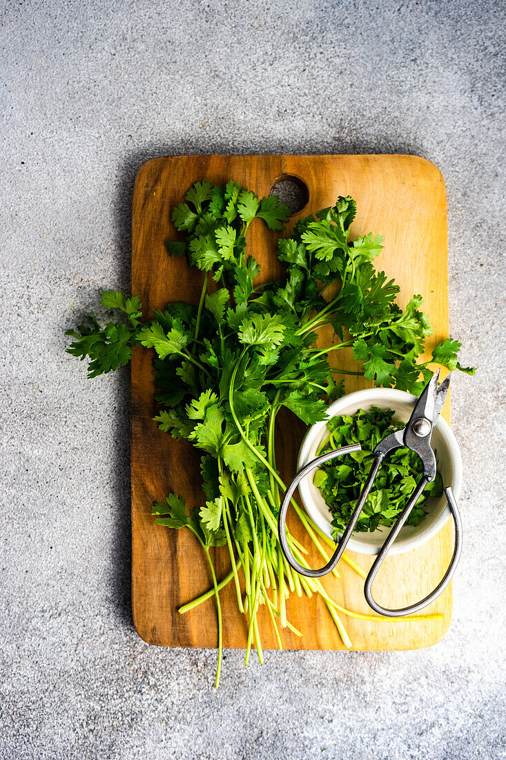 From above fresh coriander herb on wooden cutting board