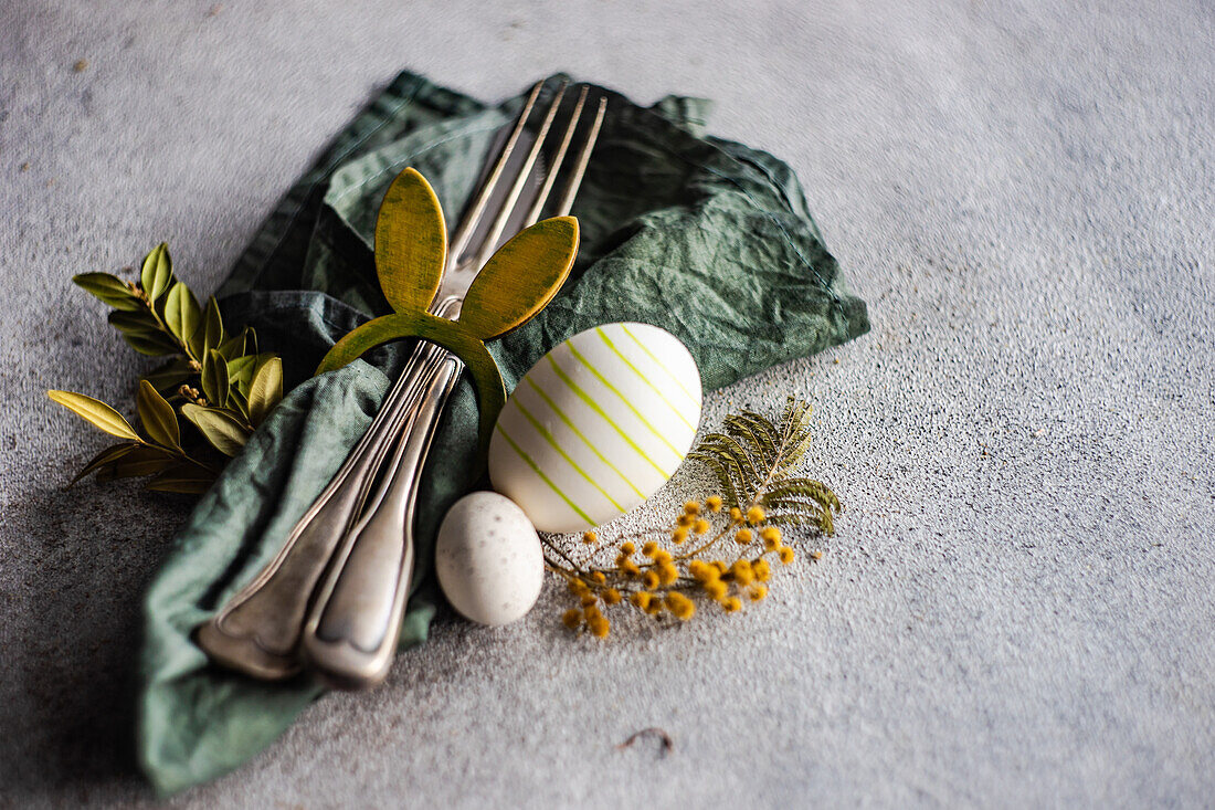 From above place setting for Easter dinner in green color on concrete background