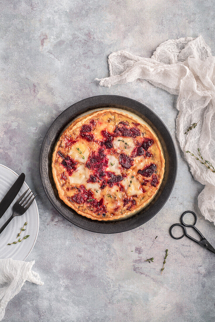 Top view of tasty whole baked pie with cream and beet on plate before eating on light table