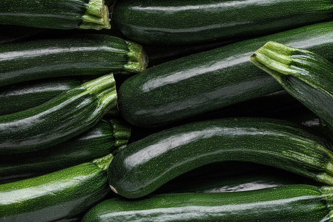 Blick von oben auf Stapel von grünen dünnen Zucchini auf dem Bauernmarkt im Hintergrund