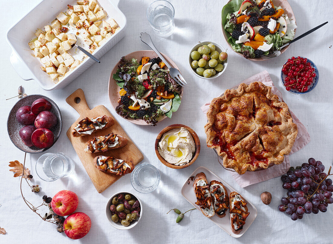 Vegetarian dinner with various snacks and dishes: salad plates, bruschetta, roasted vegetables and a pie