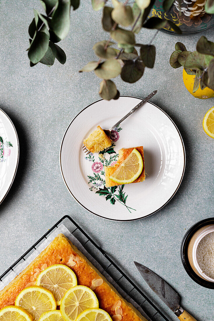 Top view of square slice of delicious homemade lemon cake served on plate with fork on tray