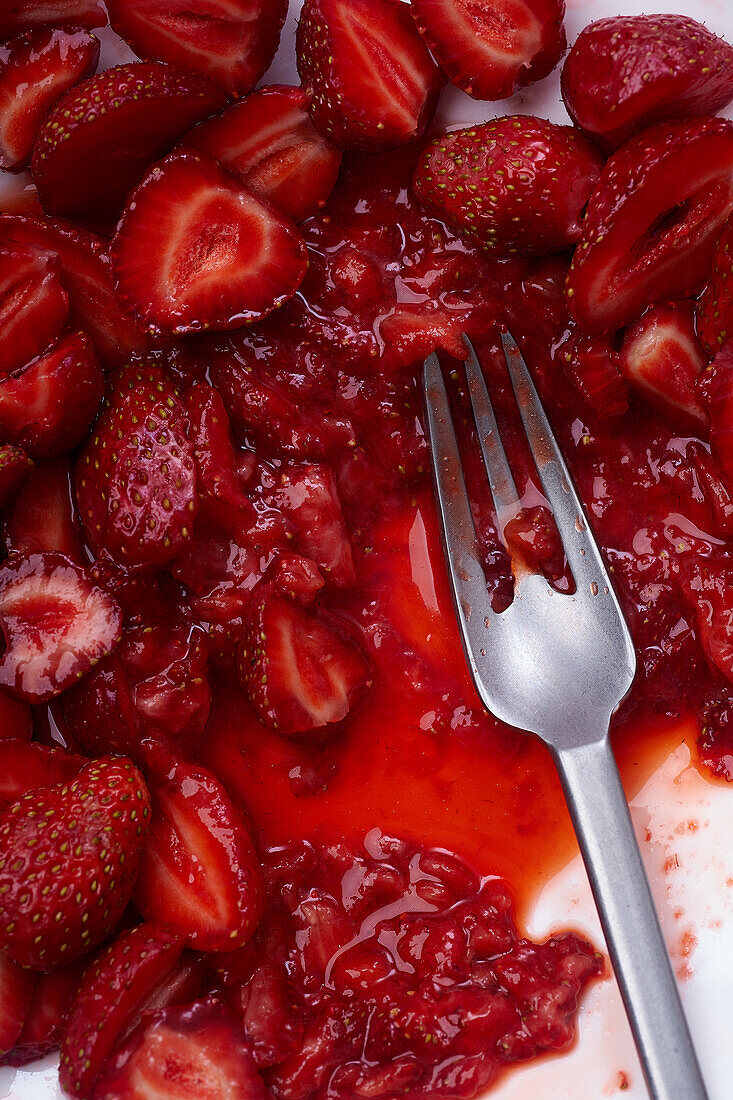 In Scheiben geschnittene Erdbeeren mit Zucker überzogen auf einem Teller. Kochen von Dessert oder Marmelade