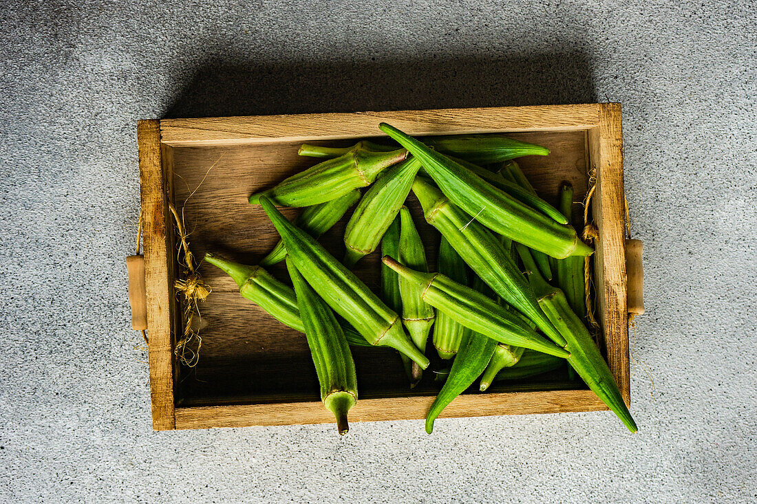 Von oben rohes und frisches Bambusgemüse in einer hölzernen Kiste auf einem Betonhintergrund