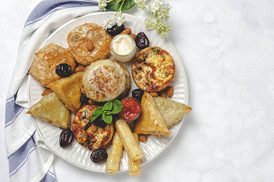 High angle of assorted tasty Arabic food with salsa and fresh mint leaves near almonds during Ramadan holidays