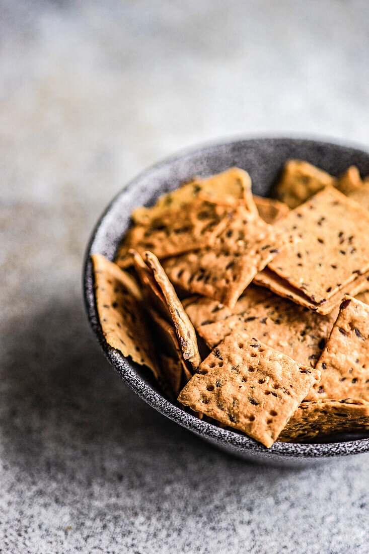 Bowl of healthy flax and sesame seeds chips on the concrete background