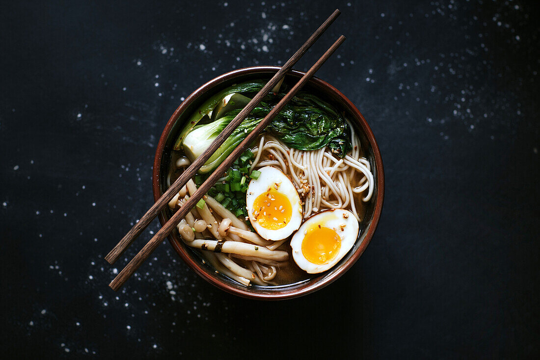 Top view of ceramic bowl with delicious ramen and chopsticks placed on table