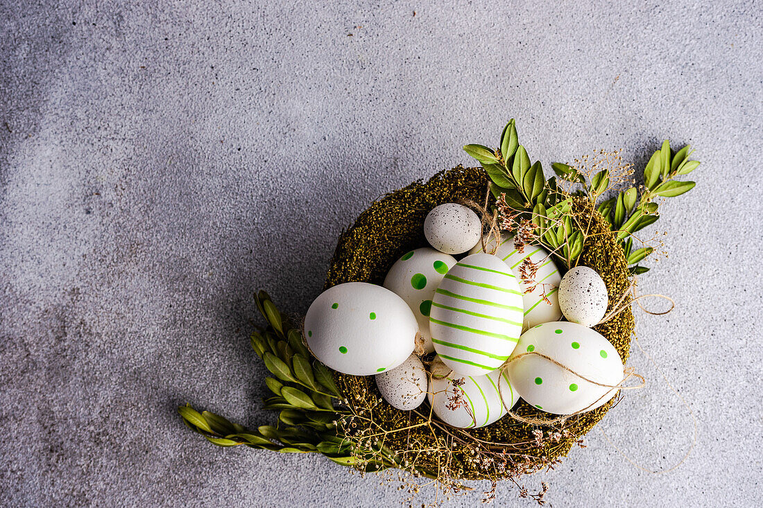 Von oben Nest voll von farbigen Eiern als Osterferien Konzept auf konkreten Hintergrund