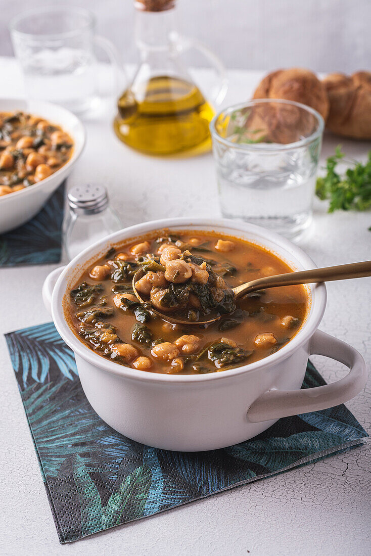 High angle of bowl with tasty chickpea soup served for lunch on paper napkin near spoon