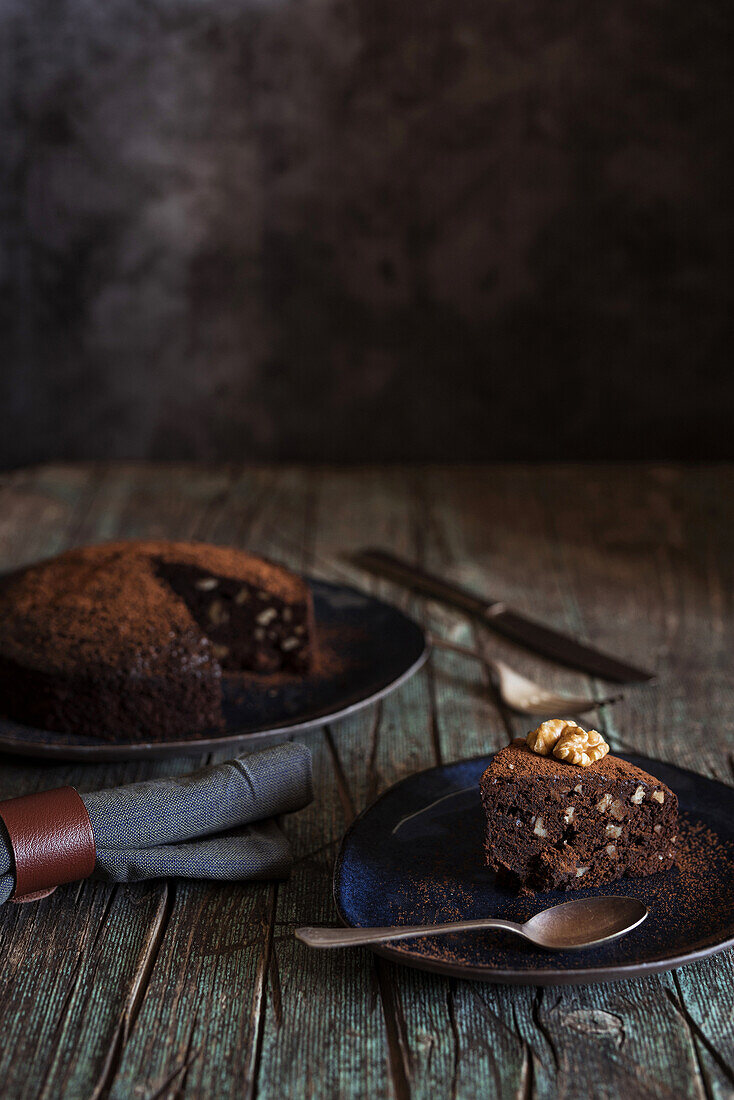 Detail of Piece of brownie cake with walnuts on a dish on wood background