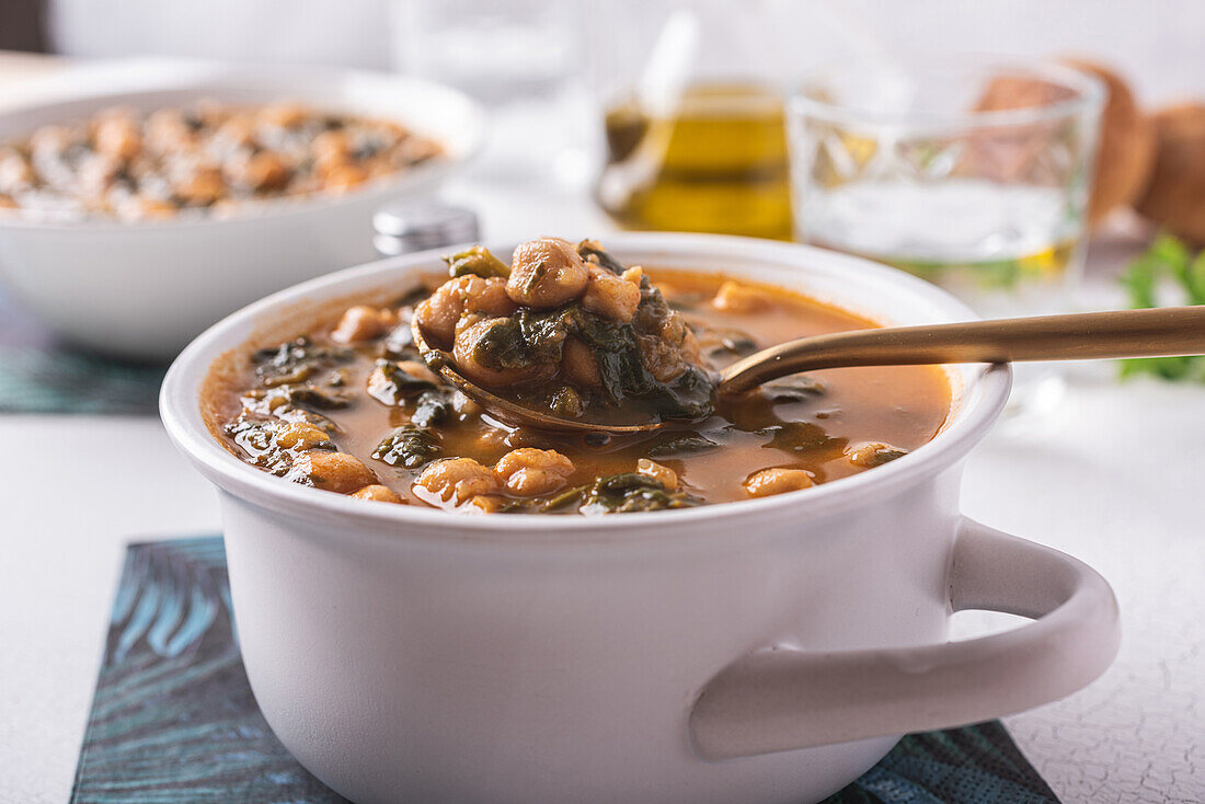 High angle of bowl with tasty chickpea soup served for lunch on paper napkin near spoon