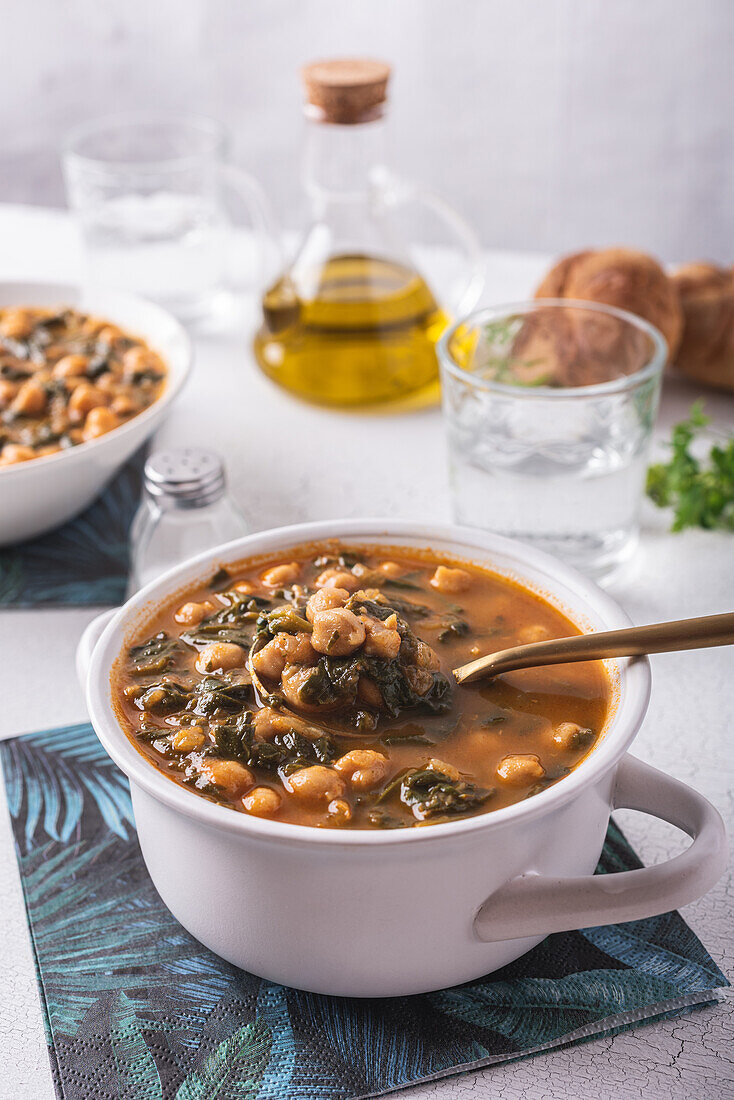 High angle of bowl with tasty chickpea soup served for lunch on paper napkin near spoon