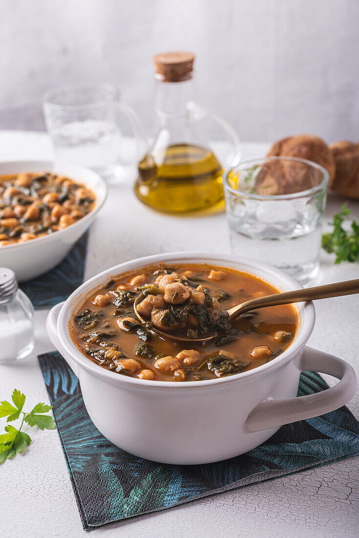 High angle of bowl with tasty chickpea soup served for lunch on paper napkin near spoon