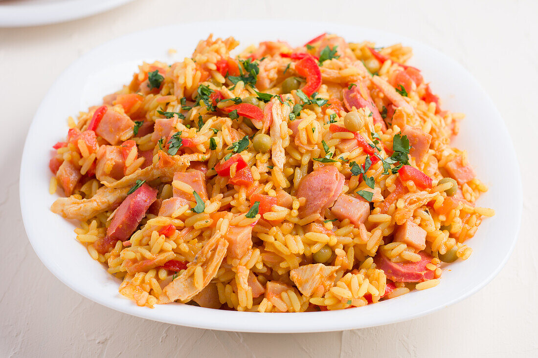 Plate with delicious rice with herbs chopped meat and vegetables on wooden stand served with oil garlic and loaf