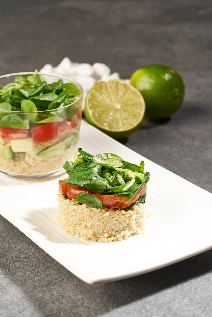 High angle of tasty salad of rice and vegetables in round shape and served in glass placed on white plate near green limes on gray table