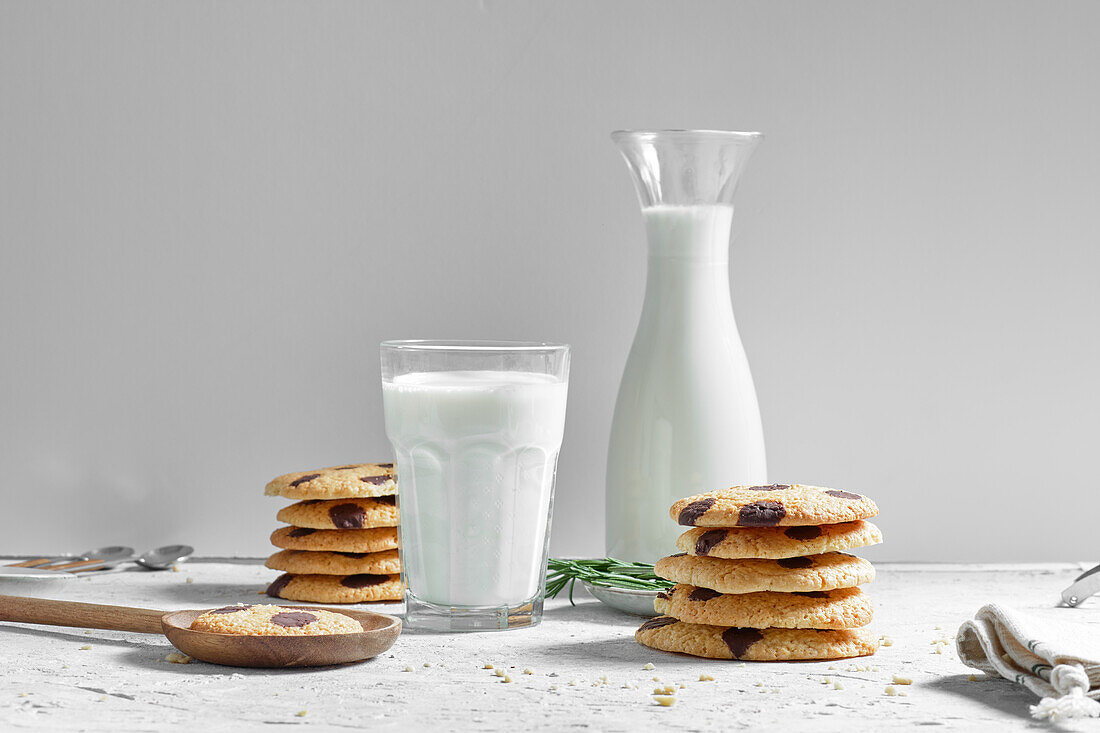 Yummy homemade freshly baked cookies with chocolate chips served with glass of milk on table
