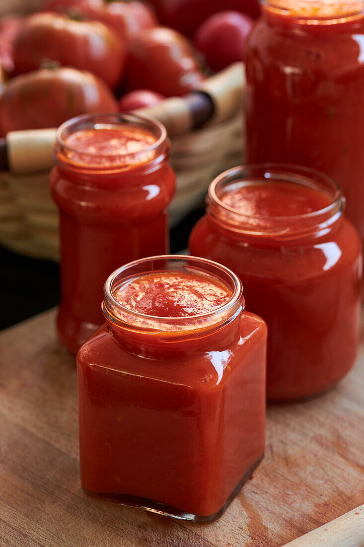 Von oben reife rote Tomaten und Gläser mit Soße auf dem Tisch in der Küche