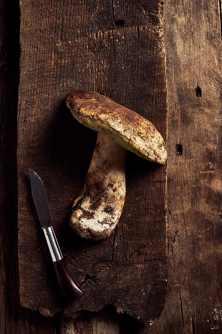 Top view of raw cut Boletus edulis mushrooms on rustic wooden chopping board during cooking process