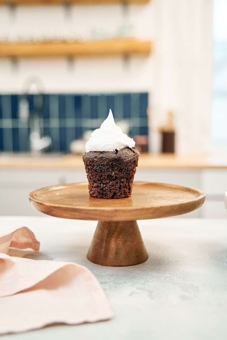 Chocolate cupcake with sweet whipped cream on cake stand at home