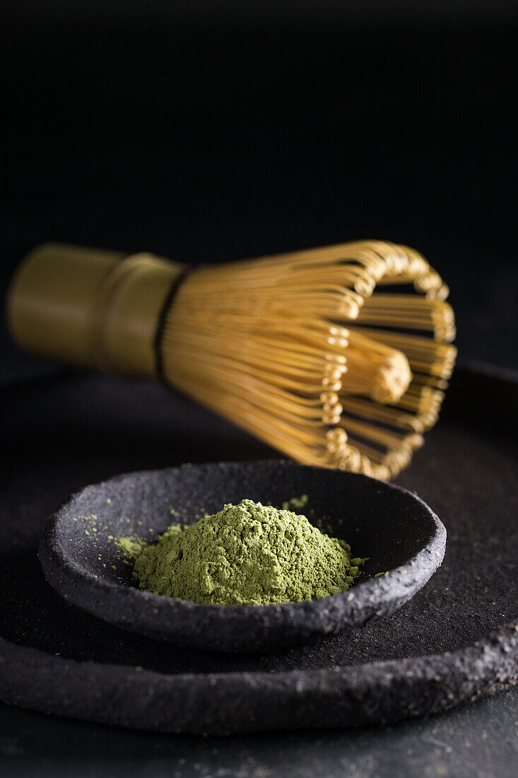 From above of dried tea leaves in heap on plate with chasen for tea ceremony