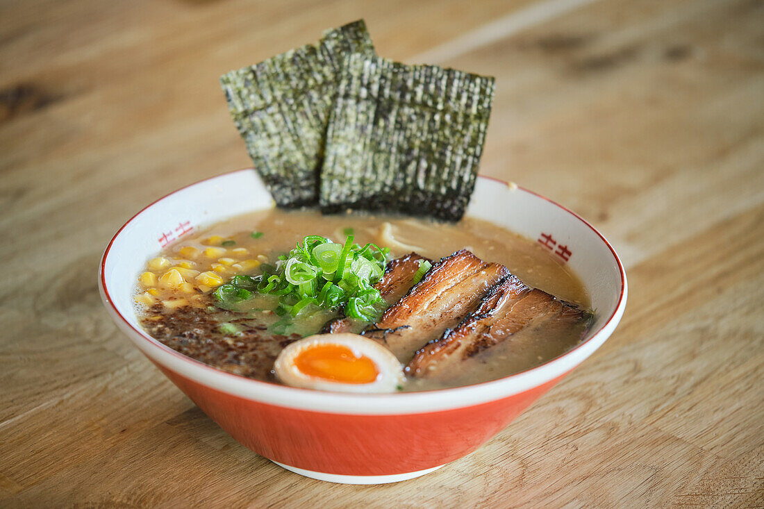 Stock photo of yummy ramen soup with boiled egg and meat in japanese restaurant ready to be served.