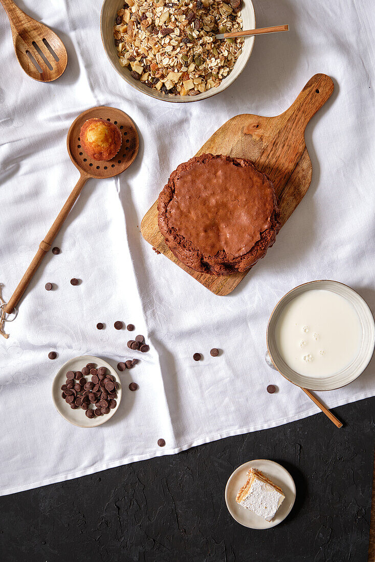 Draufsicht auf einen selbstgebackenen Schokoladen-Brownie-Kuchen, der auf einem Tisch mit verschiedenen gesunden Zutaten steht
