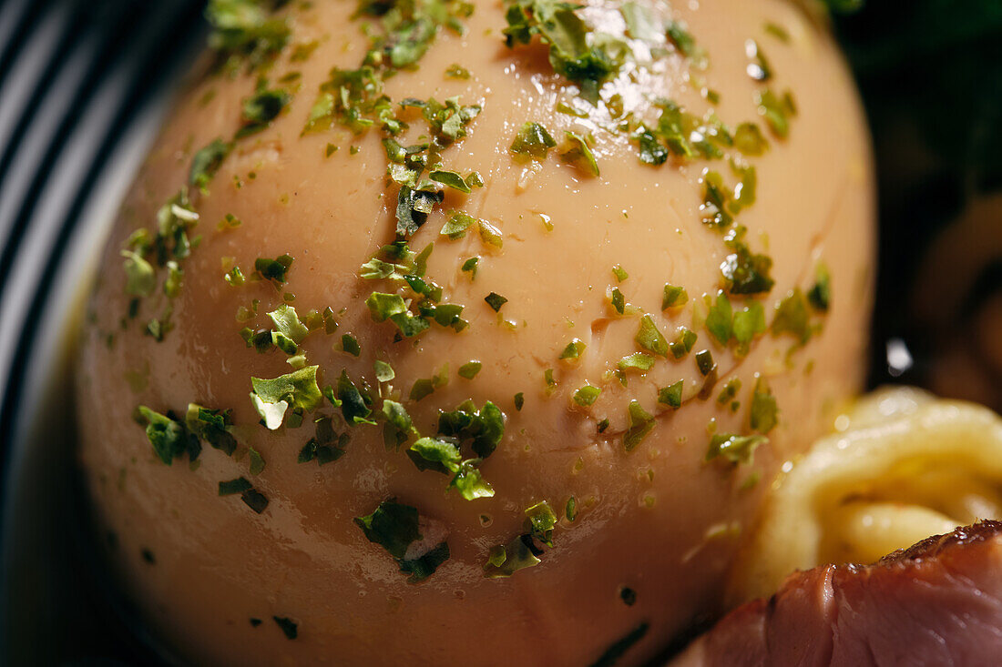 Closeup of appetizing boiled egg sprinkled with chopped herbs on plate with ramen dish