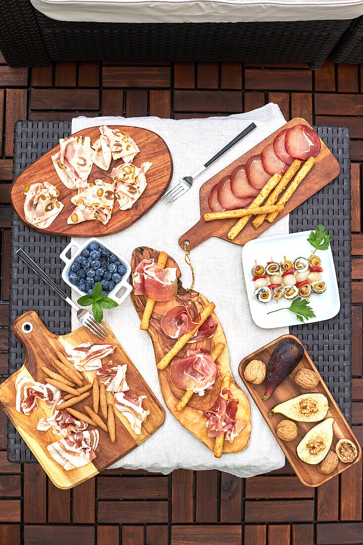 Auf einer Terrasse aufgestellter Tisch mit verschiedenen köstlichen Vorspeisen wie Serrano-Schinken, eingelegten Spießen, Nüssen usw.
