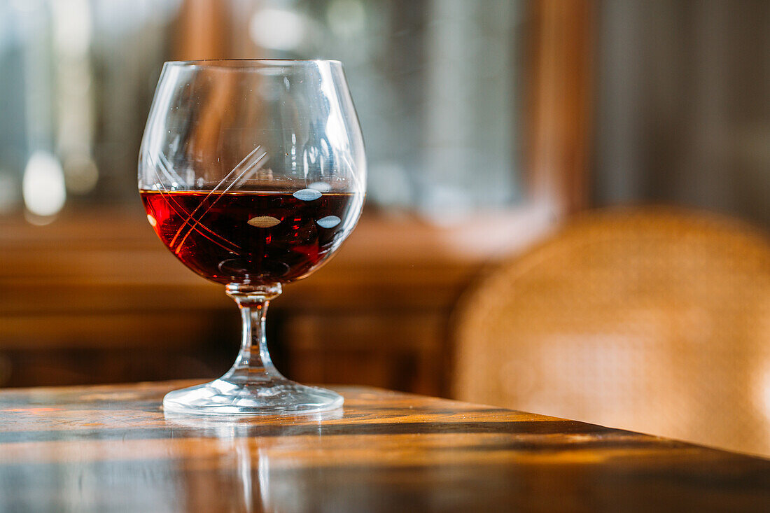 Altmodisches Cognacglas auf Holztisch mit natürlichem Licht