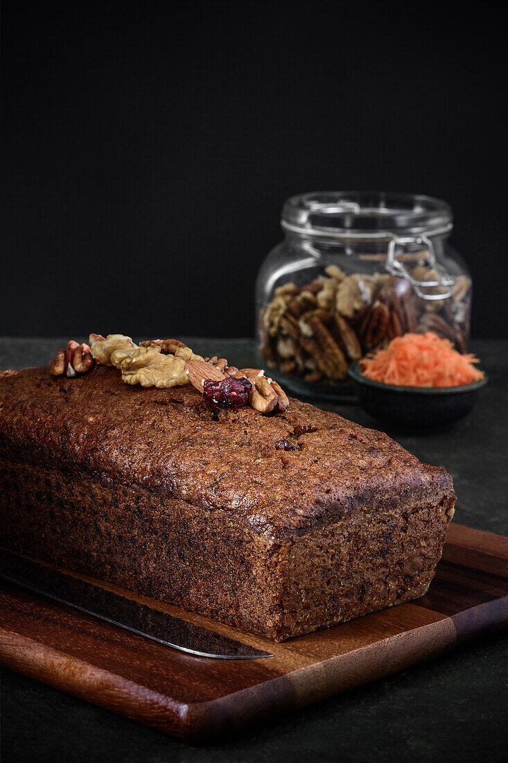 Side view of a carrot cake next to the ingredients on a rustic background