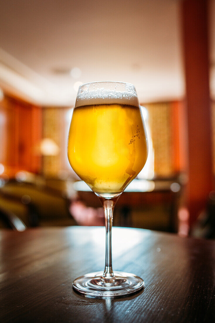 Glass of beer in a wooden table in a pub against blurred background