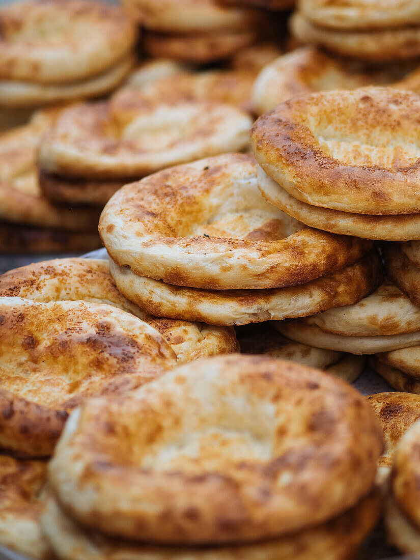 Appetizing golden baked in tandoor flatbreads of traditional Uzbekistan cuisine for sale on market