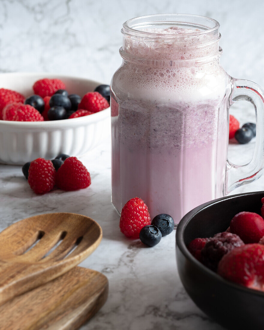 Refreshing berry smoothie in glass cup placed on table with raspberries and blueberries for healthy breakfast