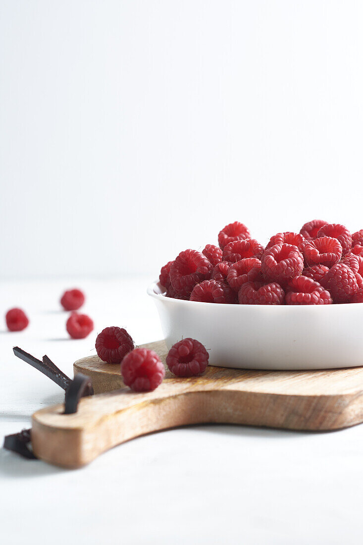 Side view of raspberries in a bowl on a wood isolated on a white background