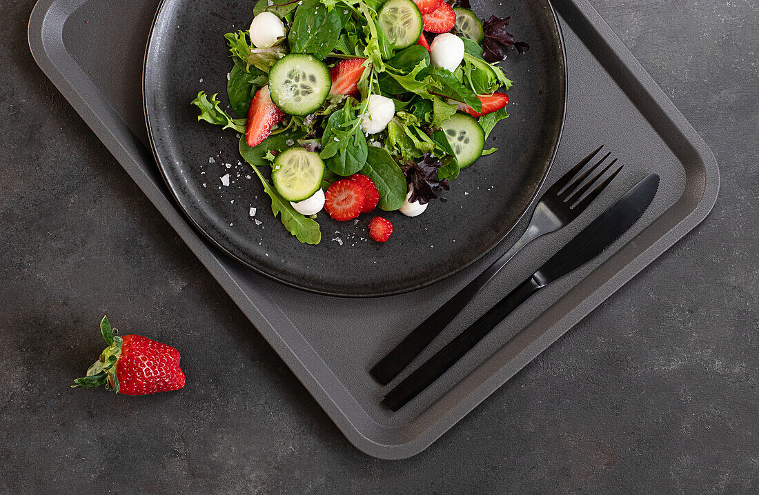 Self-service restaurant with a plate with a summery strawberry and cucumber salad on a tray