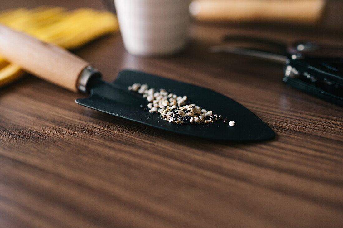 Soft focus of closeup shovel with shell gravel prepared for gardening on wooden table
