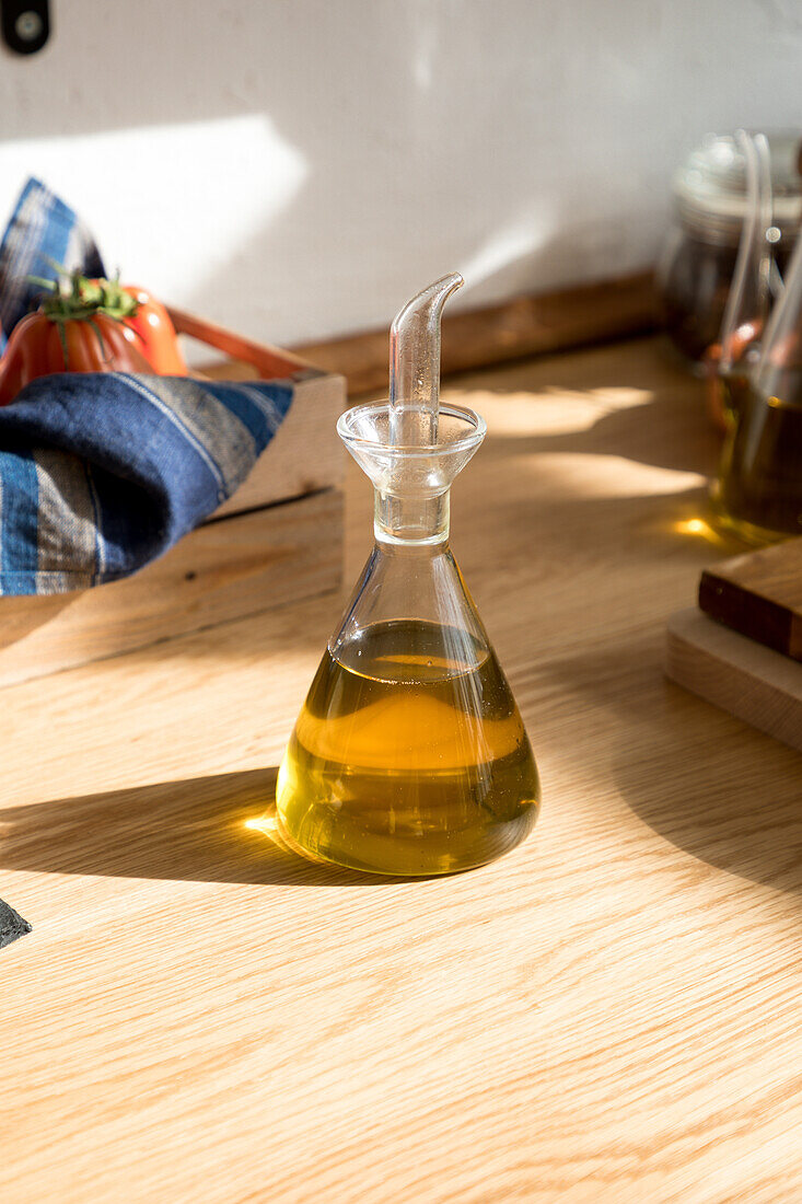Glass jar with natural aromatic olive oil placed on wooden table in home kitchen