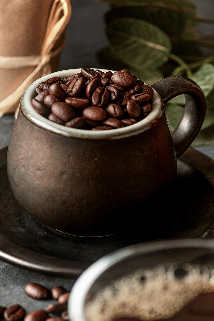 High angle of ceramic mug full of roasted coffee grains placed on table