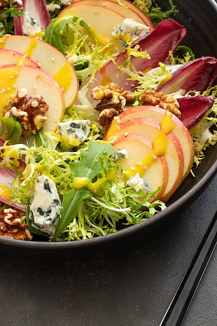 From above colorful delicious salad with endives, apple and roquefort cheese on dark background
