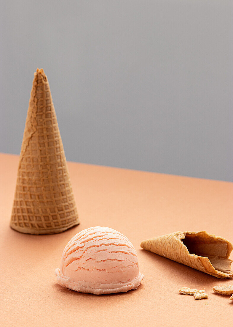 Rosa Eisportionierer und Waffeltüten auf dem Tisch im Studio