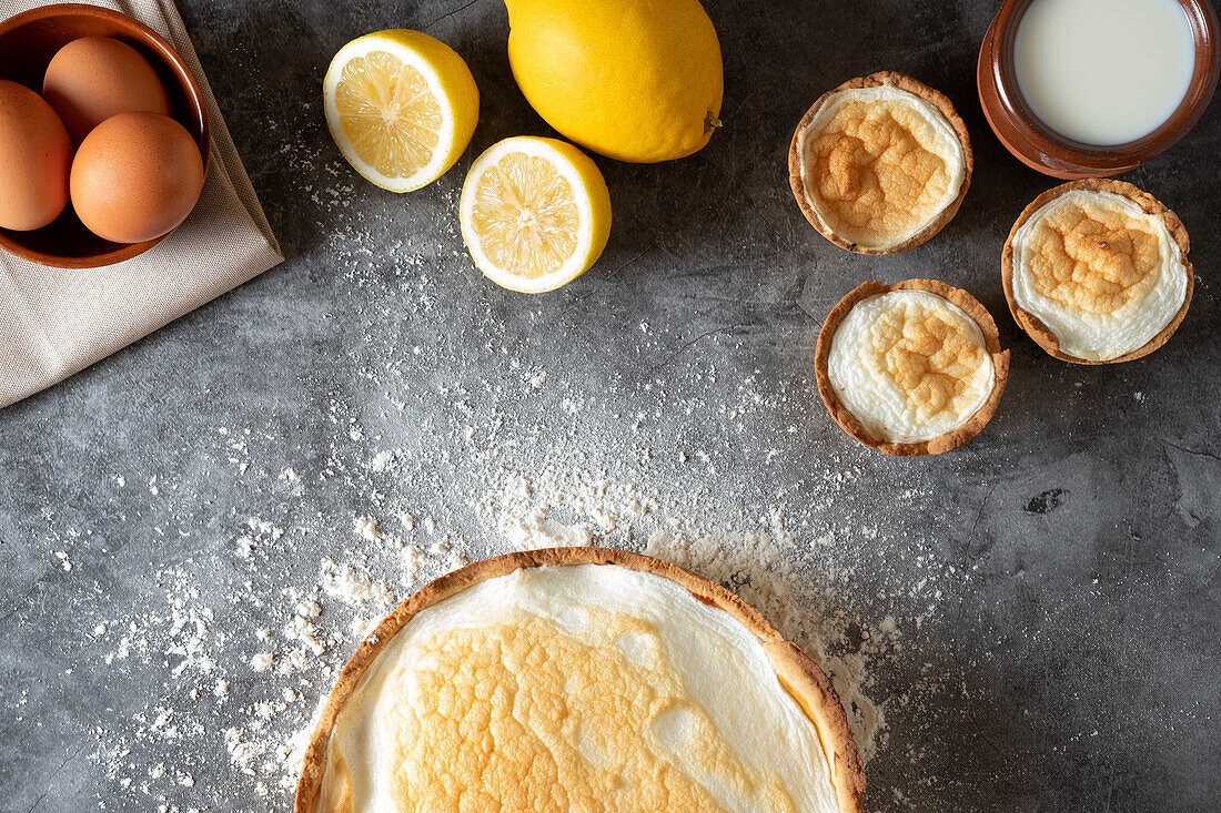 Top view of appetizing meringue pie served on marble table with fresh lemons in kitchen