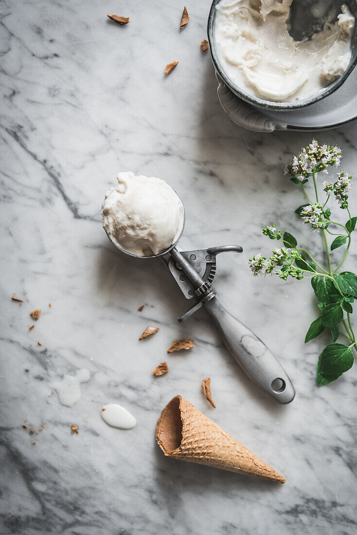 From above of waffle cone near meringue milk gelato scoops and fresh mint leaves on marble table