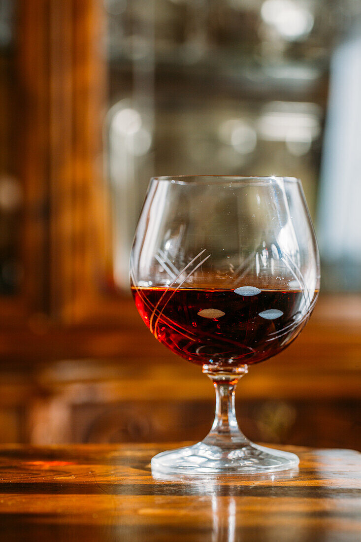 Altmodisches Cognacglas auf Holztisch mit natürlichem Licht