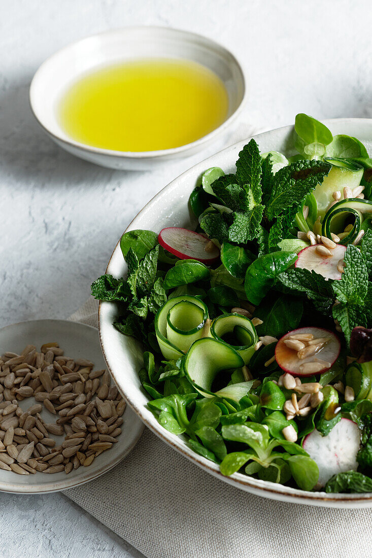 Top view of fresh healthy vegetable salad in bowl served on table with olive oil and sunflower seeds