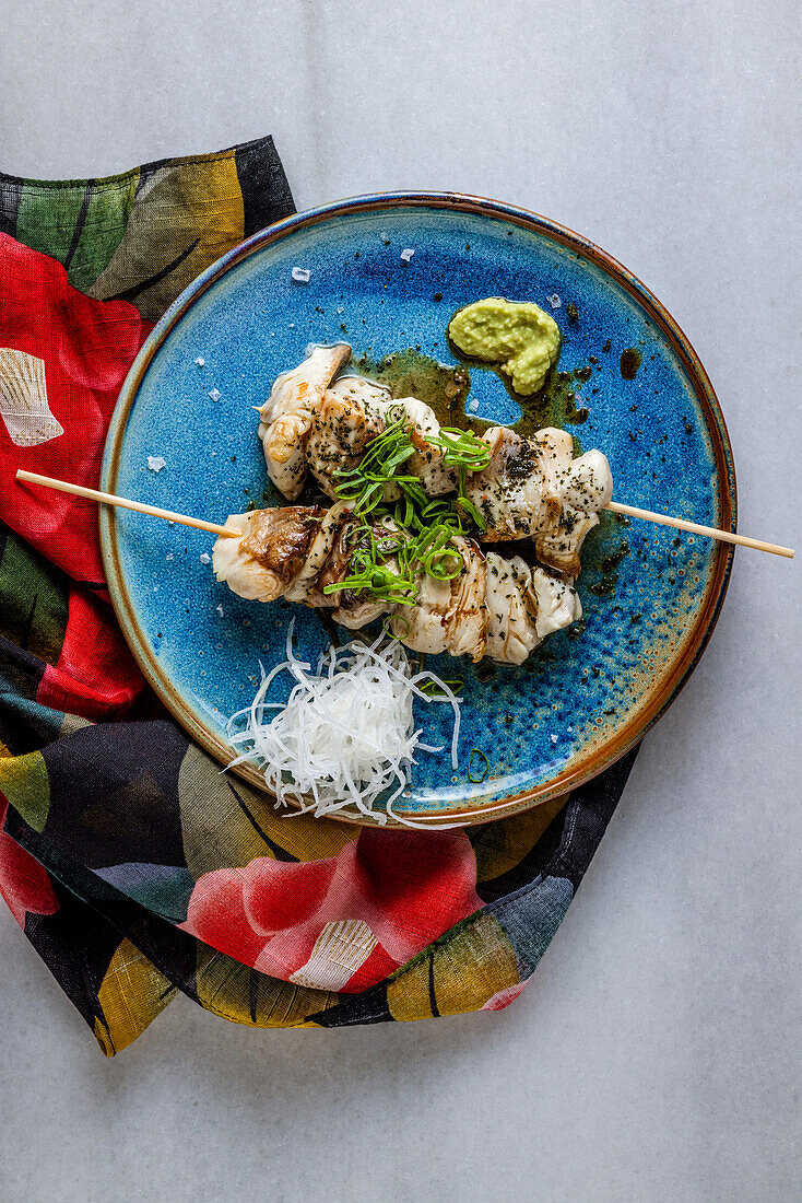 Lemon fish skewer grilled in japanese robata on blue ceramic plate