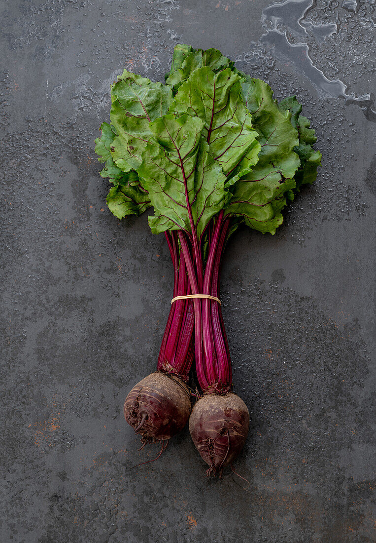From above of bunch of beet placed on black shabby background in studio